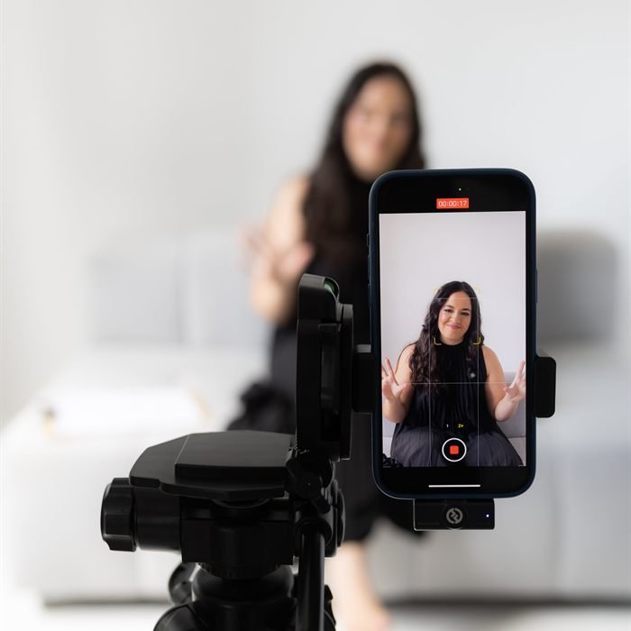 Débora Karoline gravando com o celular em um tripé, em bastidor de cobertura